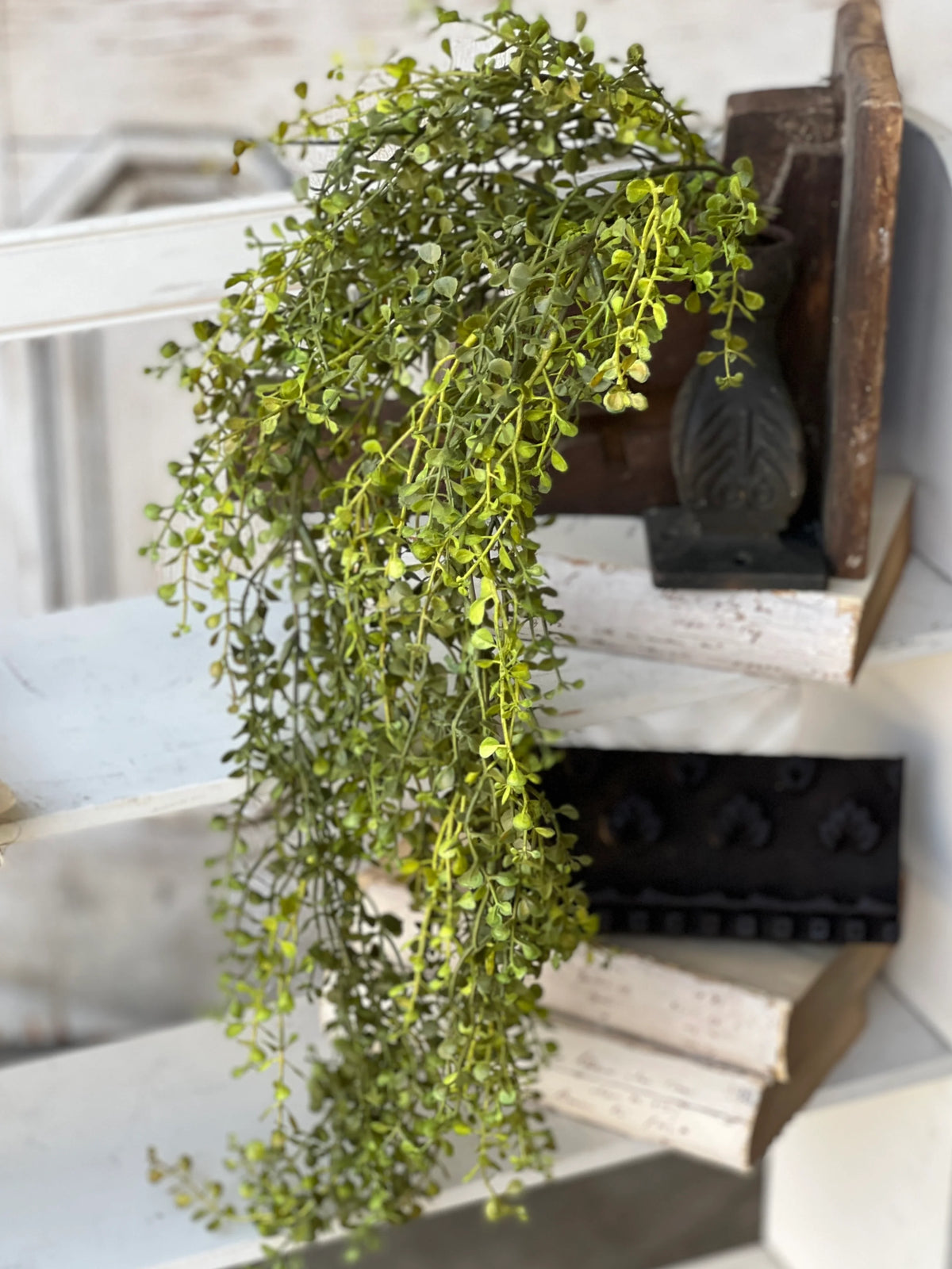 Hanging floral pick in a black vase on architectural elements.