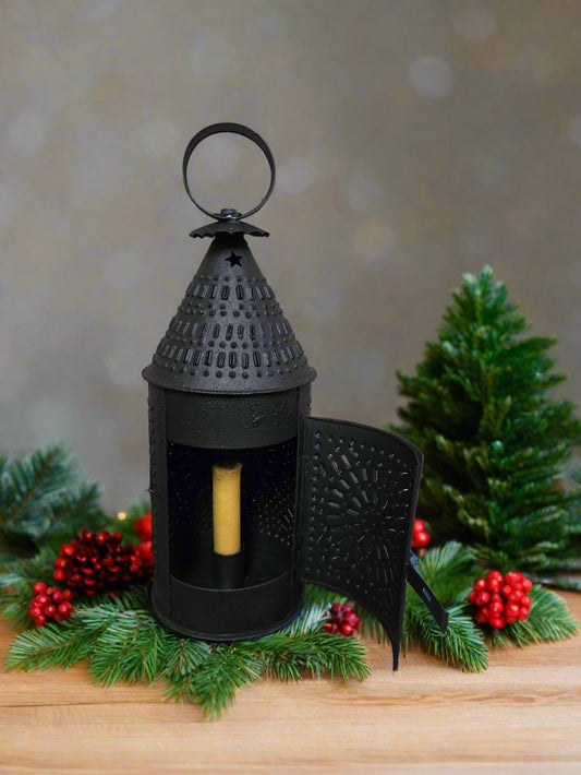 Black decorative lantern with a candle on a wooden surface with Christmas decorations.