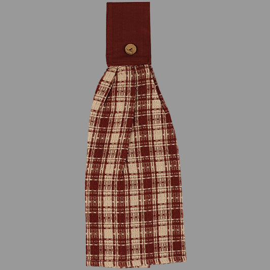 A barn red checkered hand towel with a buttoned tab on the top for hanging.