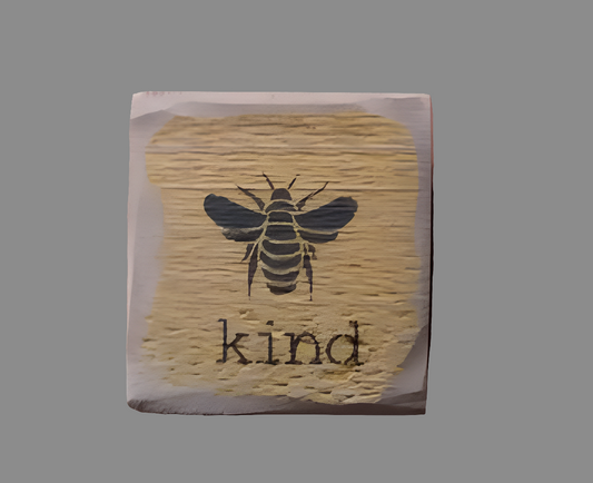 A square wooden sign with a bee illustration and the word 'kind' written on it, with a mustard and black color scheme.