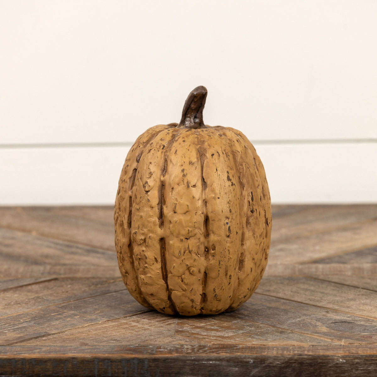 Brown pumpkin on a wooden surface with a neutral background