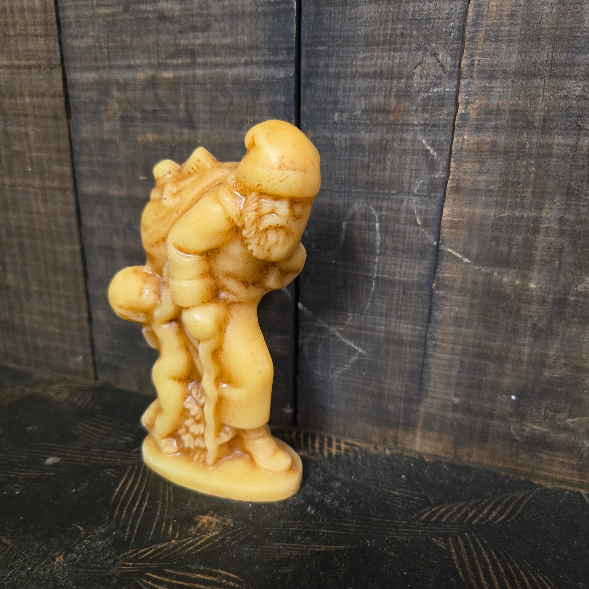 Beeswax santa with pack of toys and walking stick against weathered wood