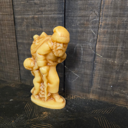 Beeswax santa with pack of toys and walking stick against weathered wood