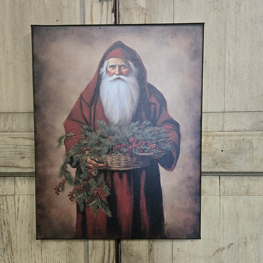 Framed artwork of a figure with a red hood and greenery on a wooden surface