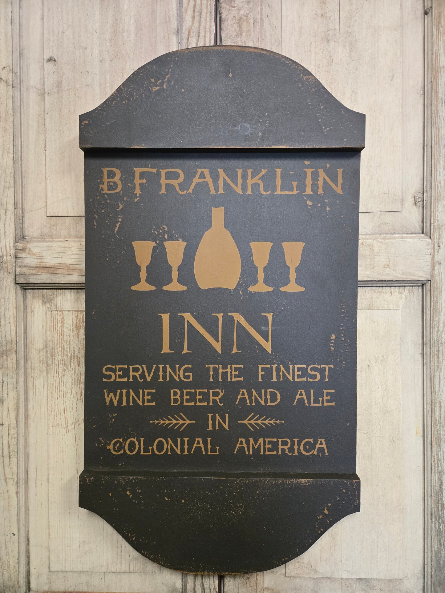 Decorative sign for B. Franklin Inn with text about beer, wine, and ale on a wooden background.