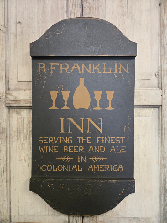 Decorative sign for B. Franklin Inn with text about beer, wine, and ale on a wooden background.