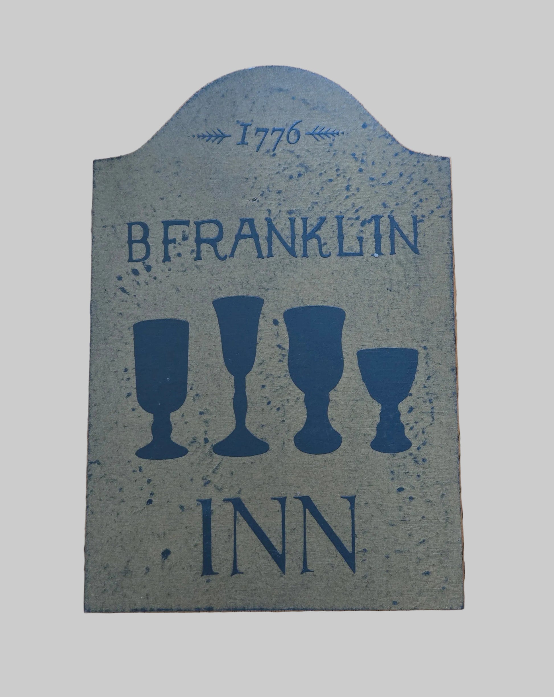 Decorative sign with 'B. Franklin Inn' and goblet illustrations on a wooden background