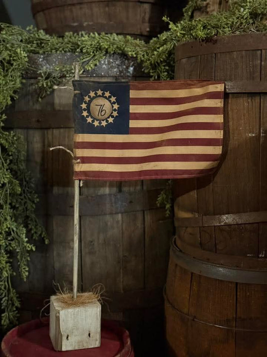 Vintage-style American flag with a decorative emblem on wooden barrels and greenery.