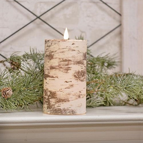 Birch bark candle on a windowsill with greenery and a light background