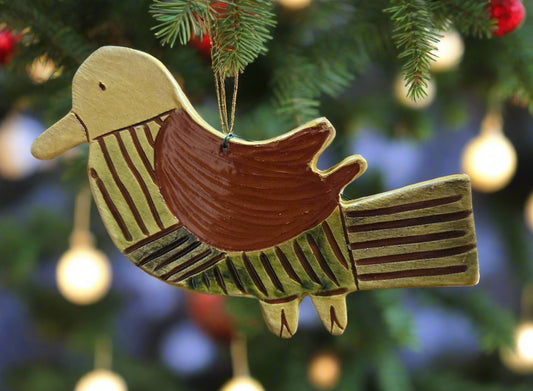 Decorative bird ornament hanging on a Christmas tree with blurred lights in the background.