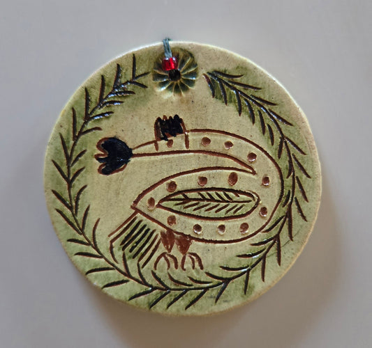 Ceramic ornament with bird and leaf design on a plain background