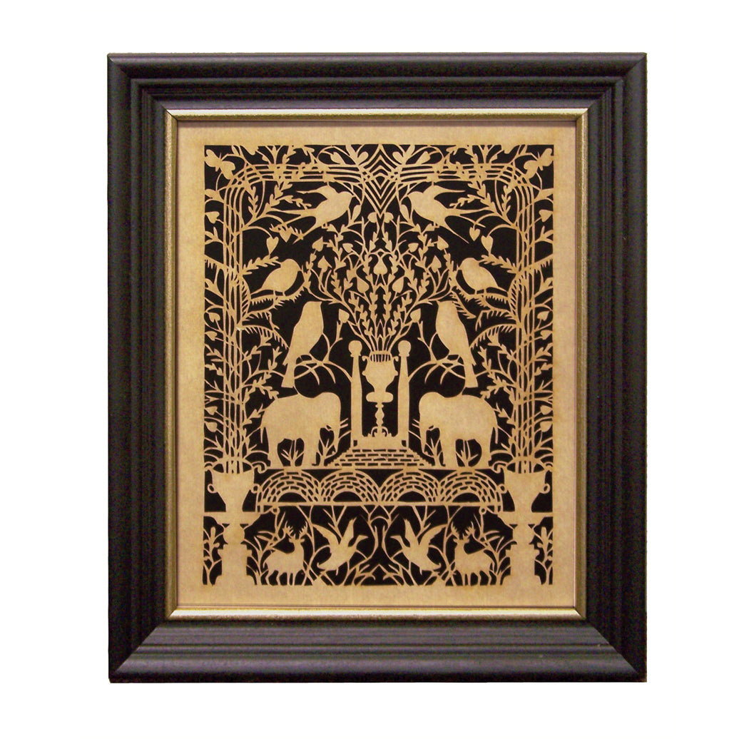 A framed scherenschnitte artwork featuring a detailed black and gold design with birds, elephants, and floral elements on a black background, housed in a black wood frame with gold edge.