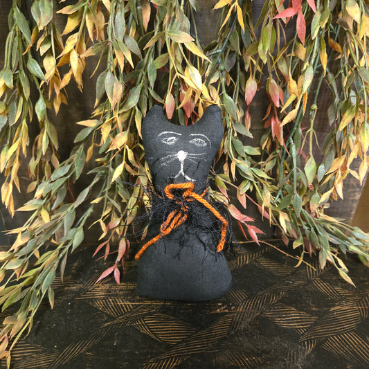 Black cat-shaped decoration with orange accents on a leafy background