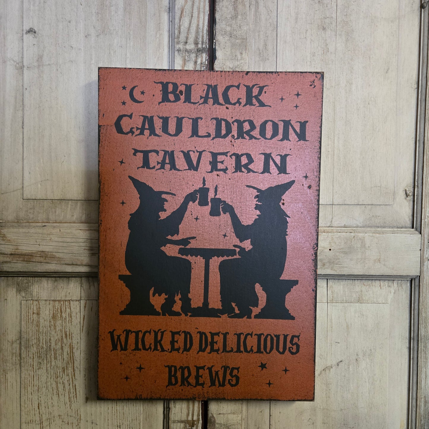 Decorative sign for 'Black Cauldron Tavern' with a witch silhouette on a wooden background