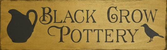 Wooden sign with 'Black Grow Pottery' text on a wooden background