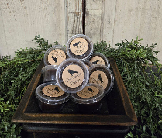 A collection of Black Crow Wax Tarts displayed in a tart warmer, surrounded by greenery.