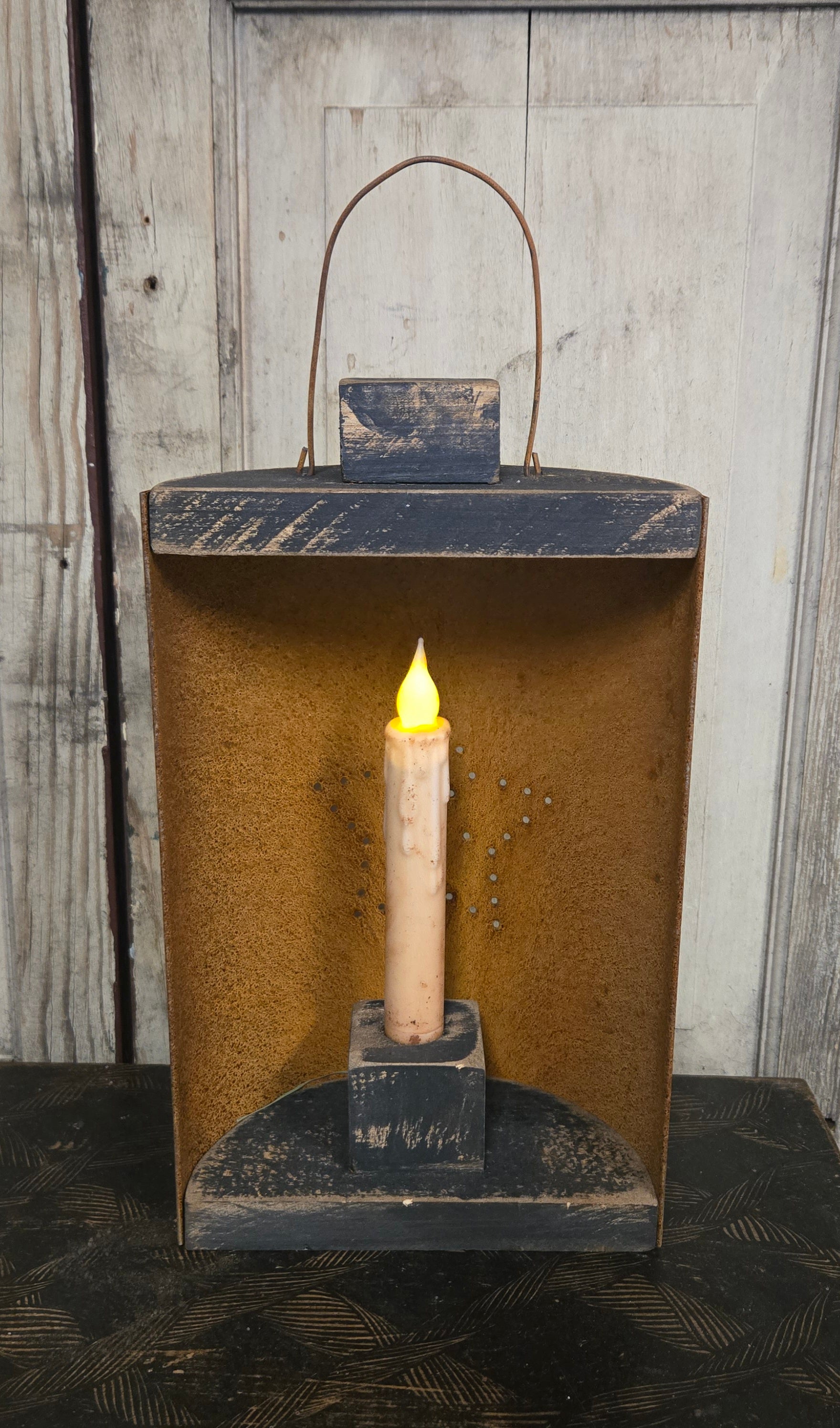 Vintage-style lantern with a lit candle inside against a wooden background