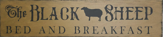 Wooden sign with 'The Black Sheep Bed and Breakfast' on a wooden background
