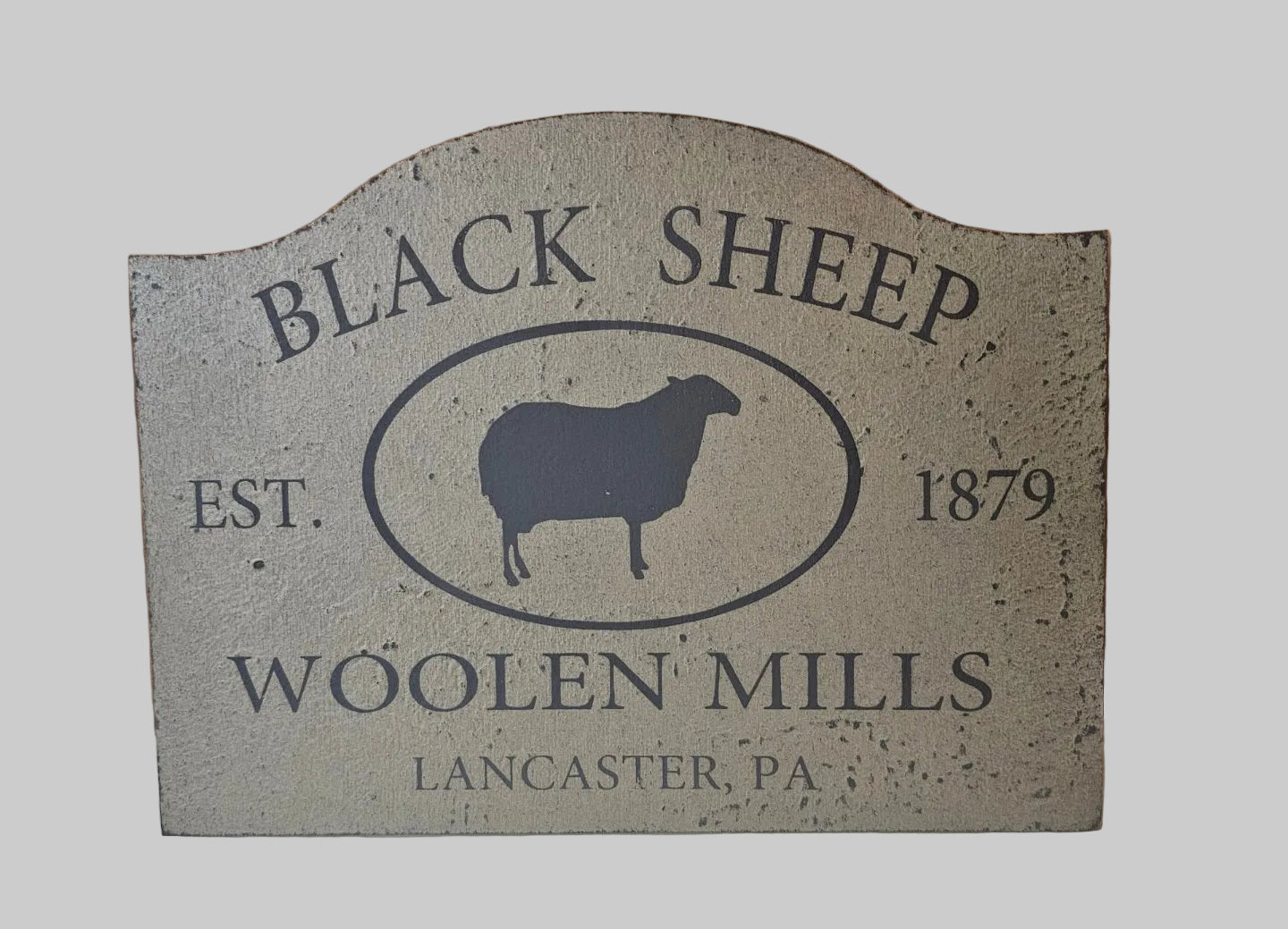 Decorative sign for Black Sheep Woollen Mills with a sheep silhouette and establishment year on a light gray background.