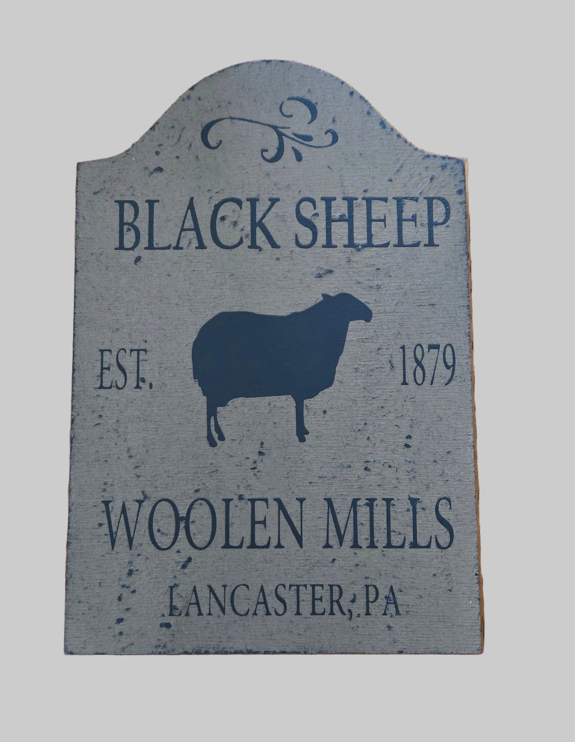 Decorative sign for Black Sheep Woollen Mills with a sheep silhouette on a wooden background