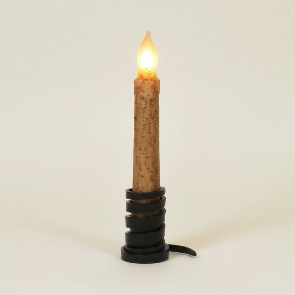 Flickering candle on a wooden stand with a label in front of a wooden background