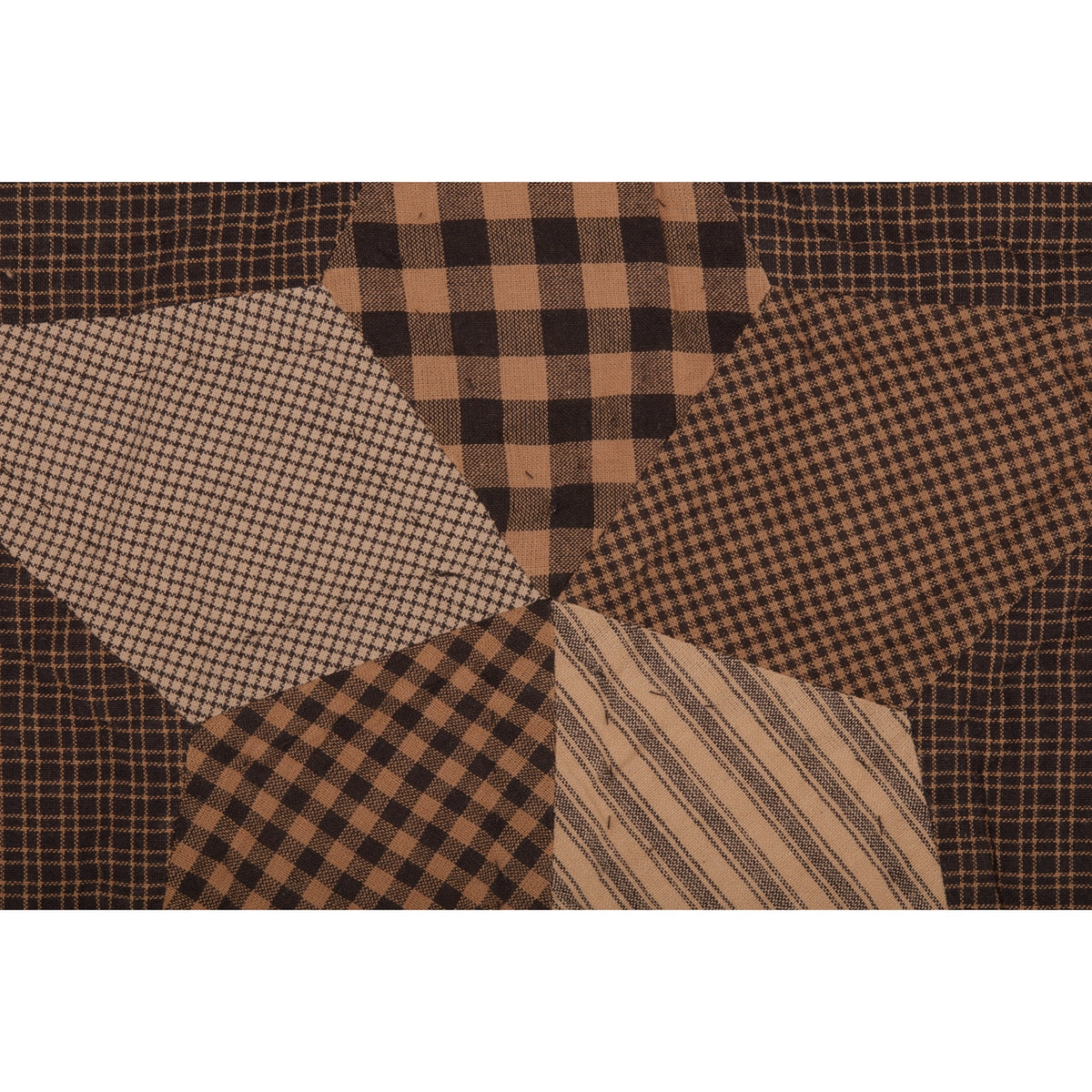Close-up of a patchwork star with black and tan checked, striped, and tiny patterned fabrics on a dark plaid background.