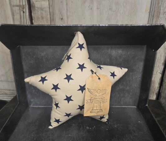 Star-shaped pillow with navy blue stars on a black tray against a wooden background