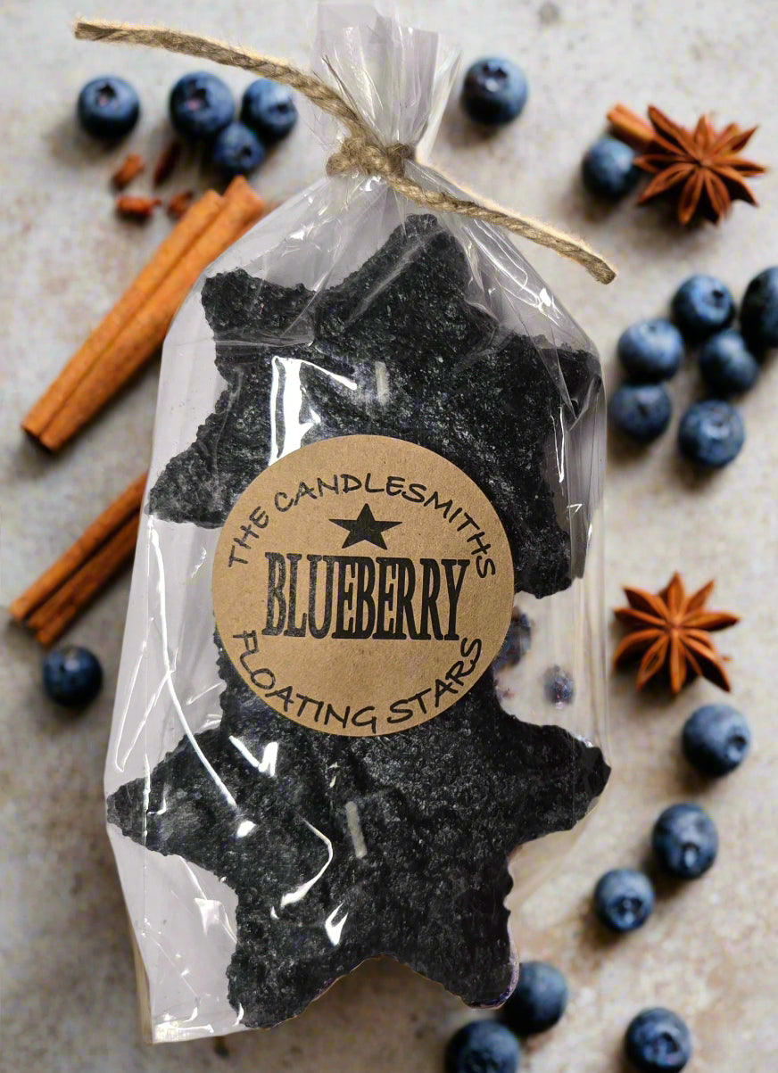 A pack of two blueberry-scented floating candles, shaped like stars, wrapped in clear plastic packaging with a label that reads 'The Candlesmith Blueberry'.