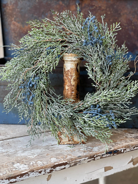 Realistic candle ring with bluestone berries with wood in background.