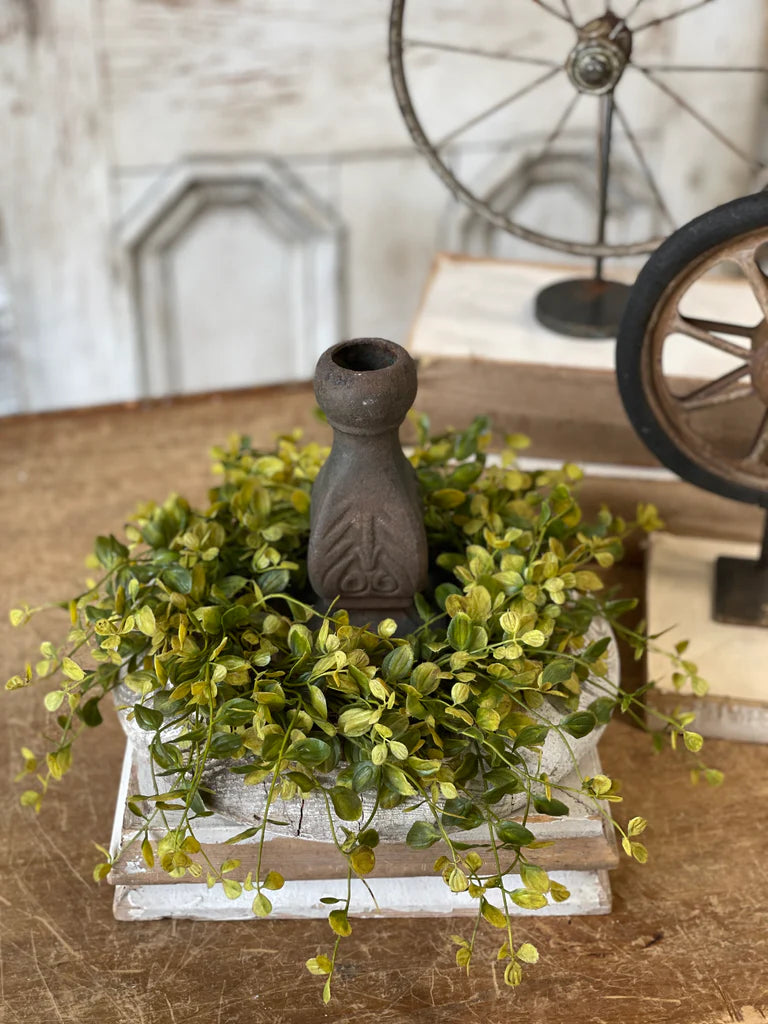 Decorative arrangement with greenery and a candle holder on a wooden surface.
