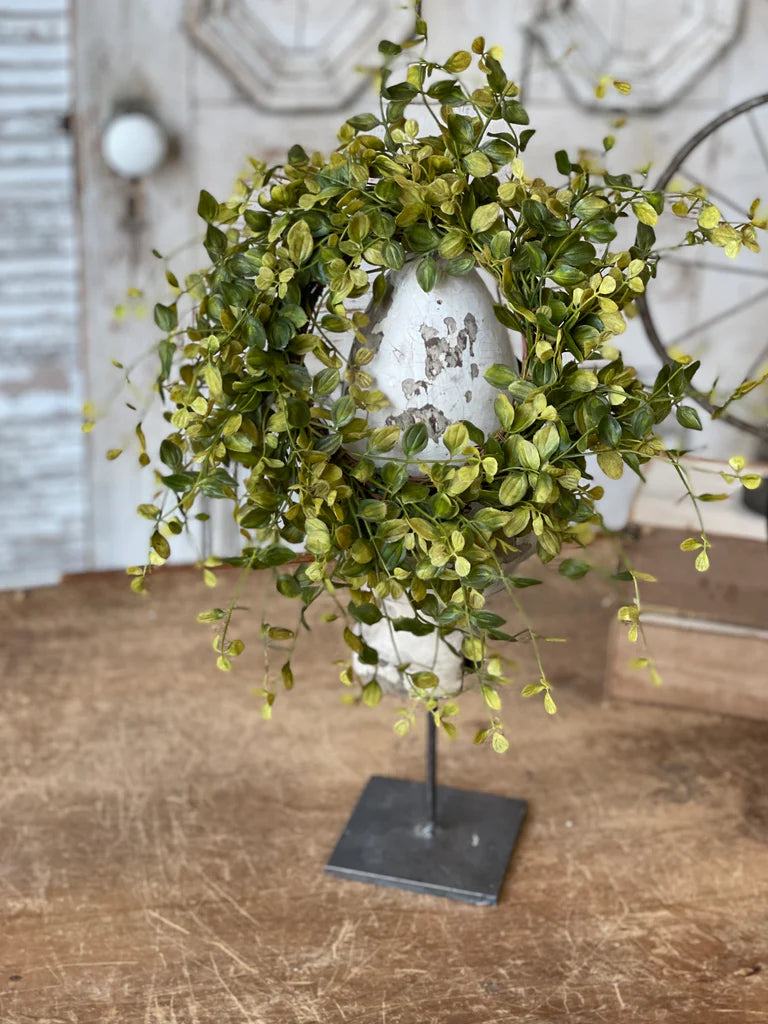 Green leafy wreath on a stand with a rustic background