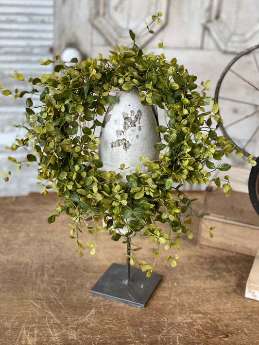 Decorative wreath with a silver egg on a wooden surface