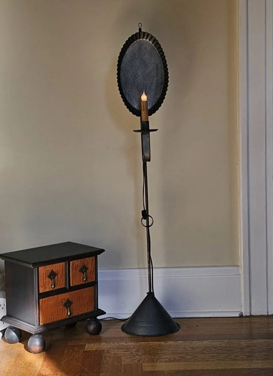 Decorative black lamp with a candle against a beige wall.