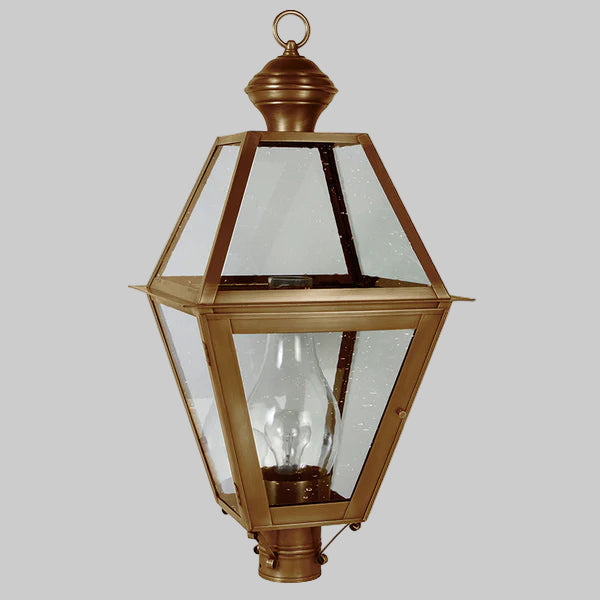 Decorative outdoor lamp with brass finish and clear glass on a gray background
