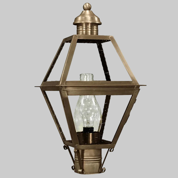 Vintage-style brass outdoor lamp with clear glass shade on a gray background
