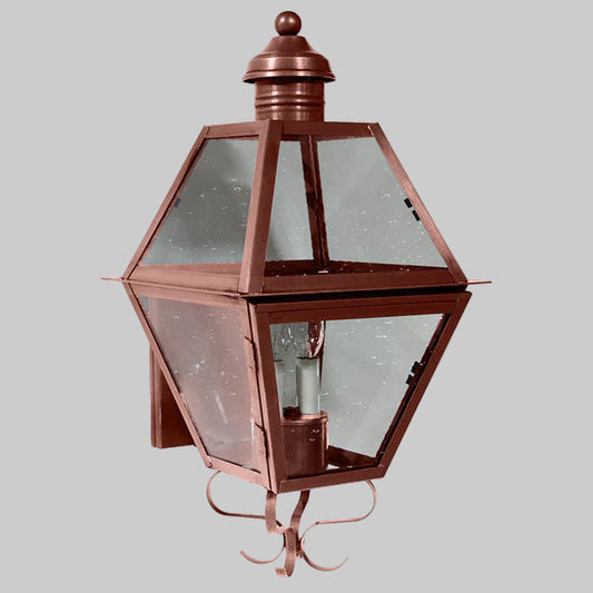 Copper outdoor wall light fixture with clear glass on a gray background