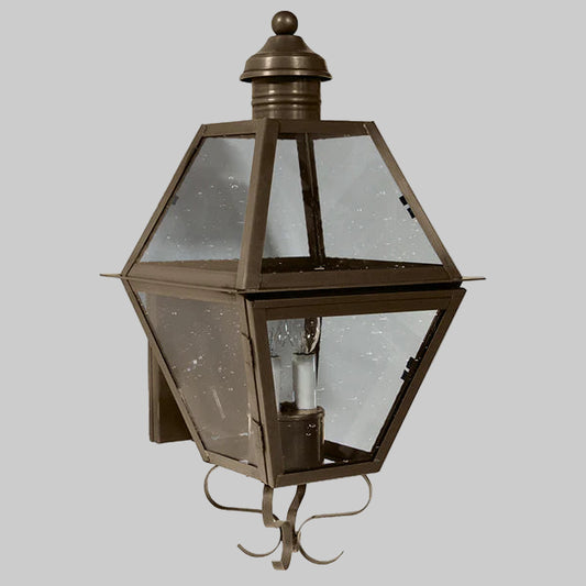 Bronze outdoor wall light fixture with clear glass on a gray background