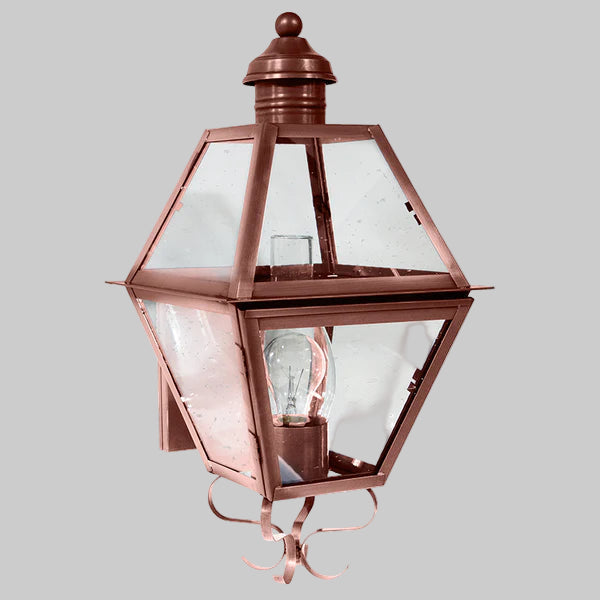 Copper outdoor wall light fixture with clear glass on a gray background