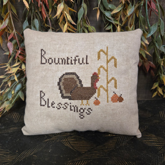 Decorative pillow with cross-stitched design of a turkey and text on a natural background