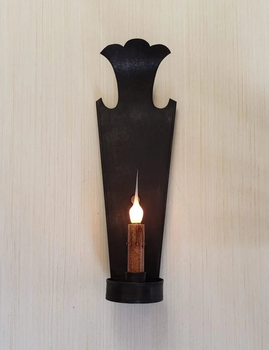 Black wall sconce with a candle on a textured white wall