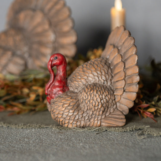 Decorative turkey figurine with a candle in a blurred natural setting