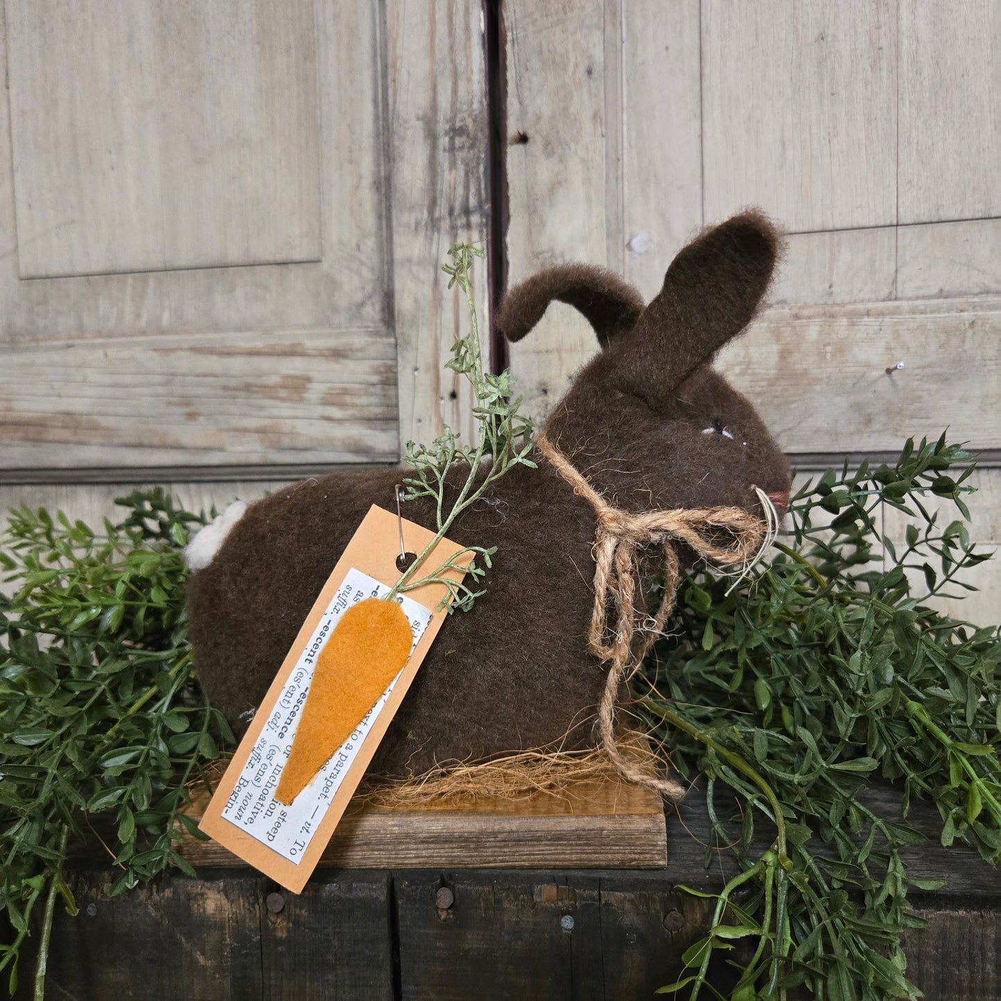 Plush brown bunny with a carrot-shaped tag on a wooden background