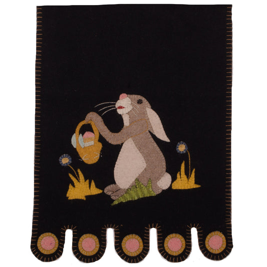 A black table runner with a whimsical bunny holding a basket in the center, surrounded by a floral motif.