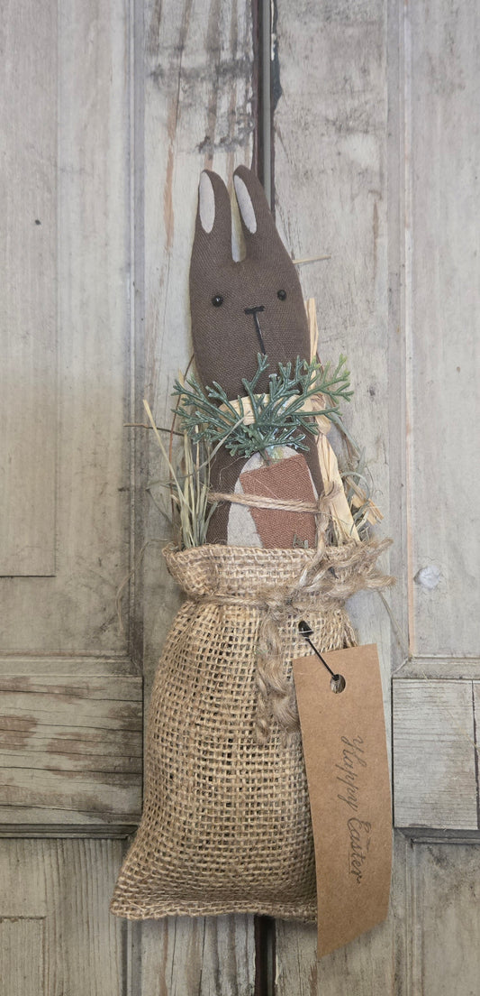 Decorative wooden bunny with a burlap bag and tag on a wooden background