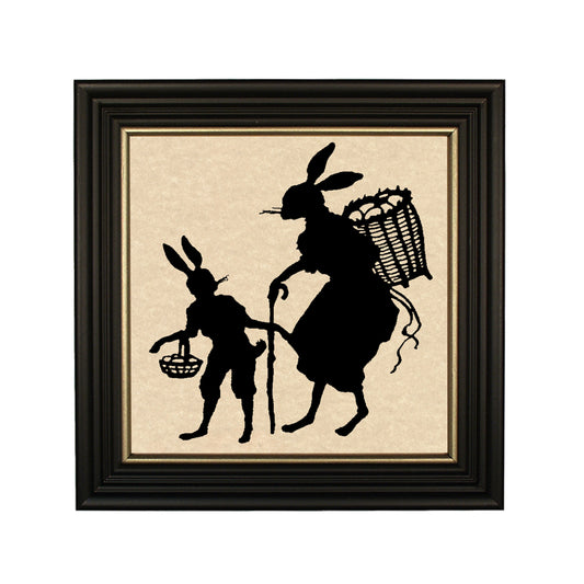 A paper cut silhouette of a rabbit with a backpack and a human-like figure carrying a basket, framed in a black solid ash wood frame with gold trim.