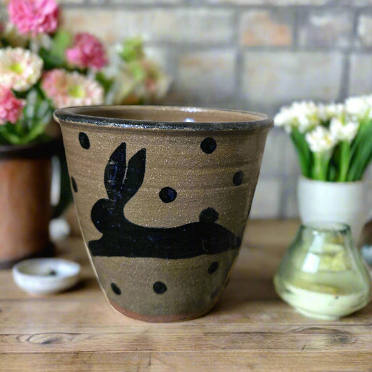 Stoneware tumbler with bunny and dots motif against weathered wood
