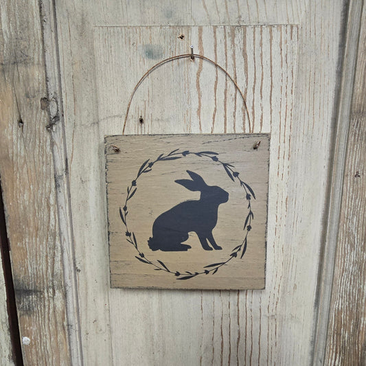 Wooden plaque with rabbit design on a rustic wooden background