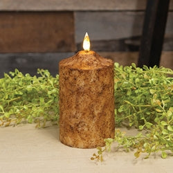Rustic candle with a flame surrounded by greenery on a neutral background