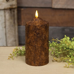Burnt mustard flicker flame timer cake pillar candle with baby grass greenery in the background.