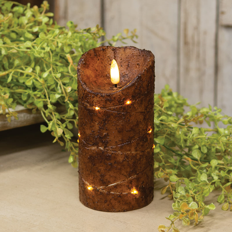 Burnt mustard LED wrapped flicker flame timer pillar with baby grass greenery in background.